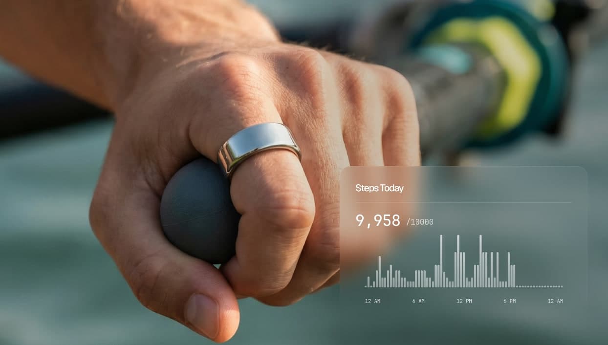 The Ultrahuman app showing 9,958 of a 10,000 daily step goal beside a hand wearing the titanium ring