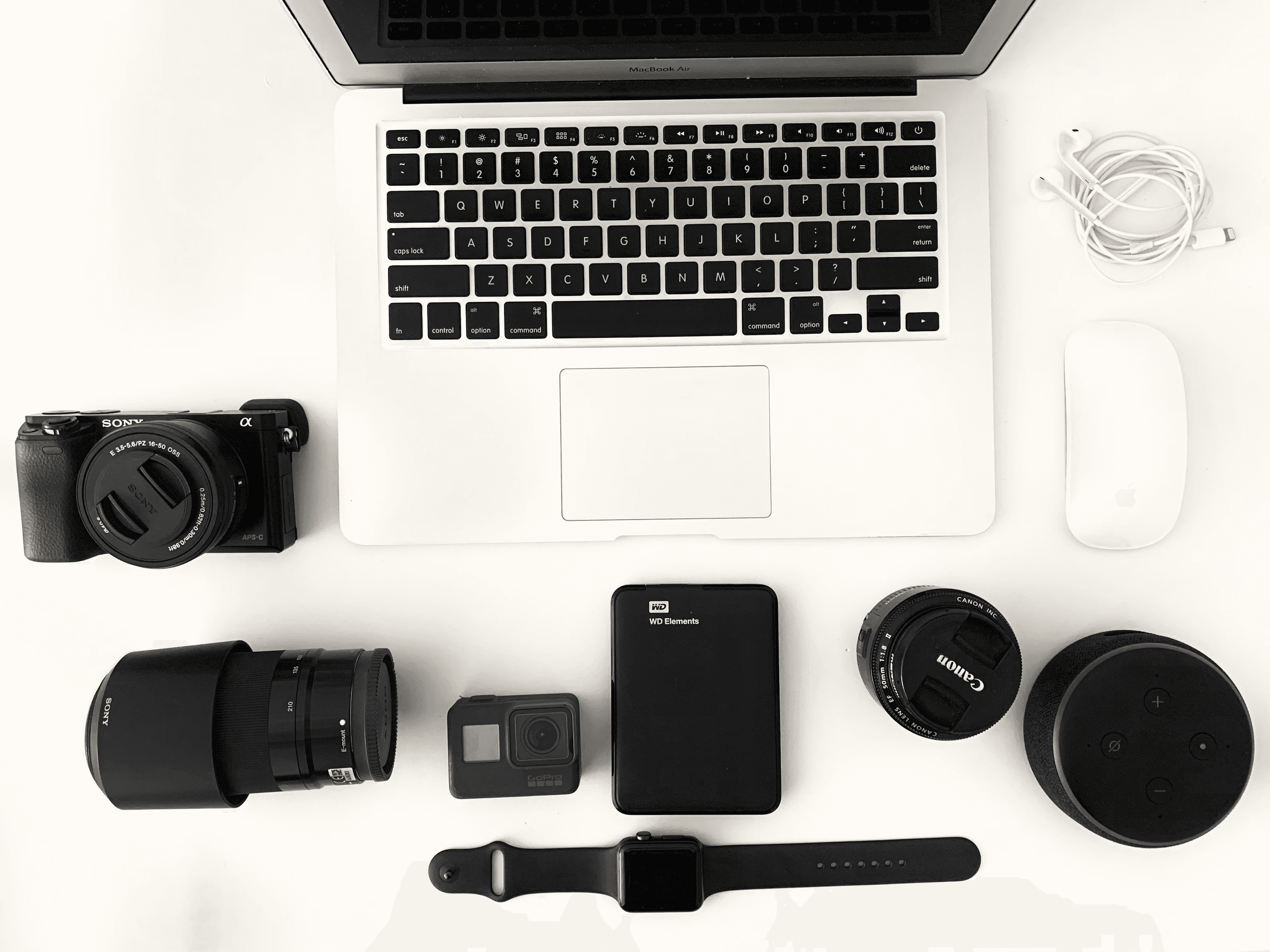 Laptop, cameras, lenses, wearable technology, and accessories arranged for product research