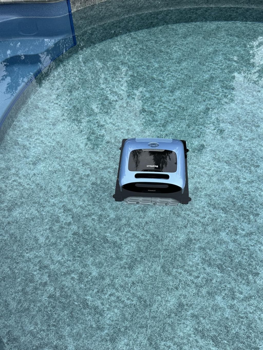 Cordless robotic pool cleaner operating on the floor of an in-ground swimming pool